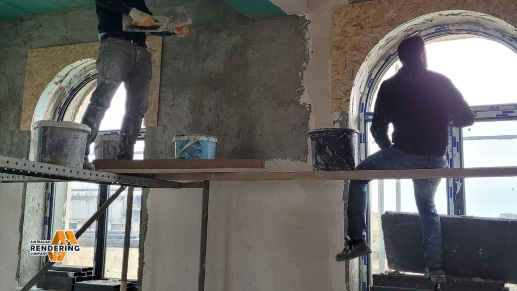 Construction workers plastering arched windows