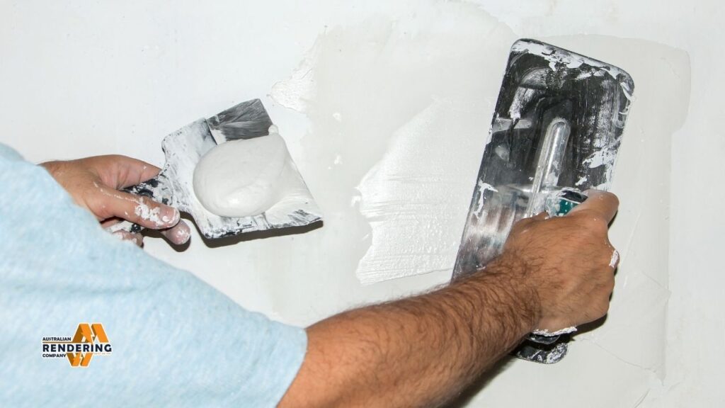 Man applying plaster to a wall with trowels