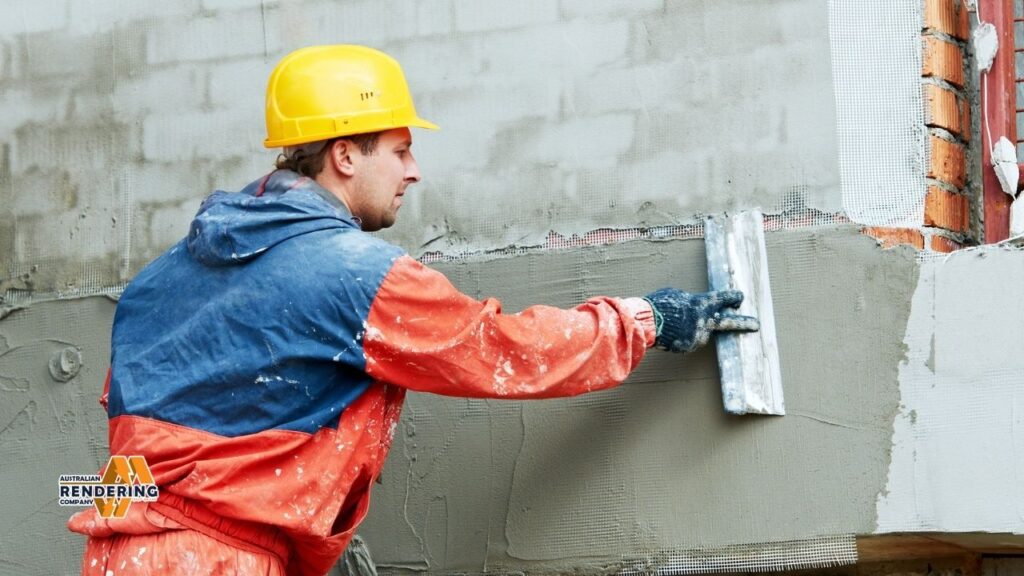 Man applying stucco to brick wall