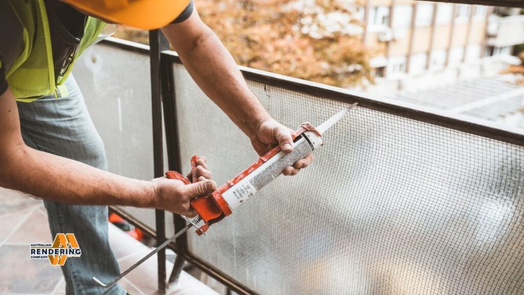 Worker caulking window screen with sealant gun