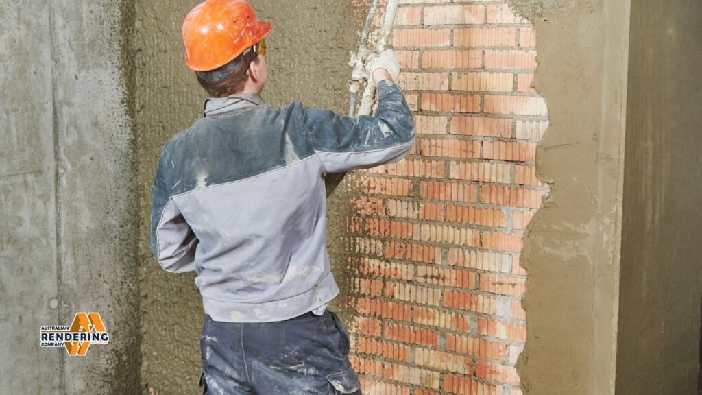 Worker rendering brick wall with cement
